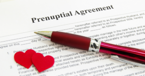 Sample prenuptial agreement document with pen and two red hearts